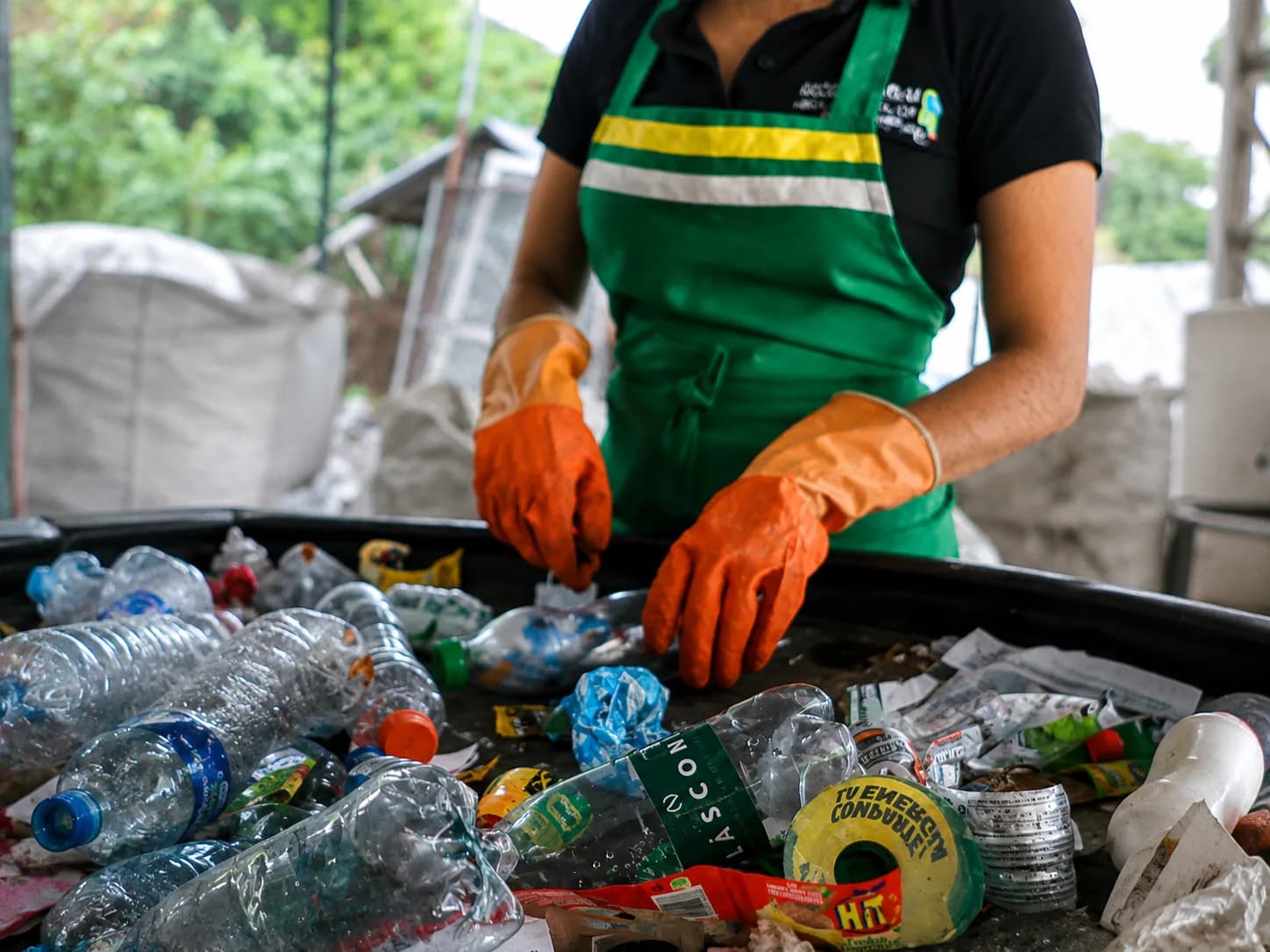 Person classification recyclable materials on a conveyor belt. Professional setting.